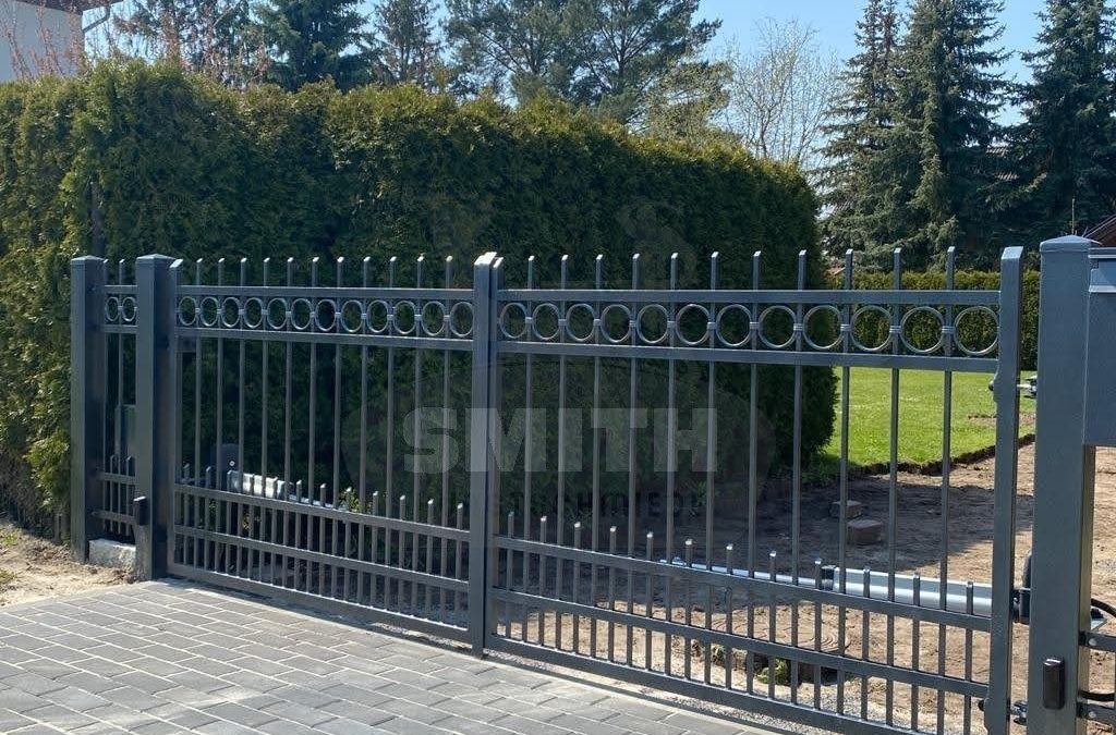 Zweiflügeliges Einfahrtstor aus Metall mit Torantrieb vor einer Hecke